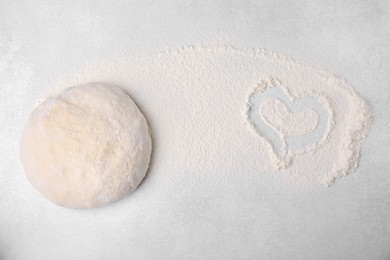 Heart made of flour and dough on light grey table, top view