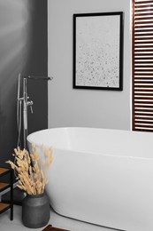 Photo of Stylish bathroom interior with ceramic tub and decor elements
