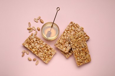 Photo of Tasty kozinaki bars, peanuts and honey on pink background, flat lay
