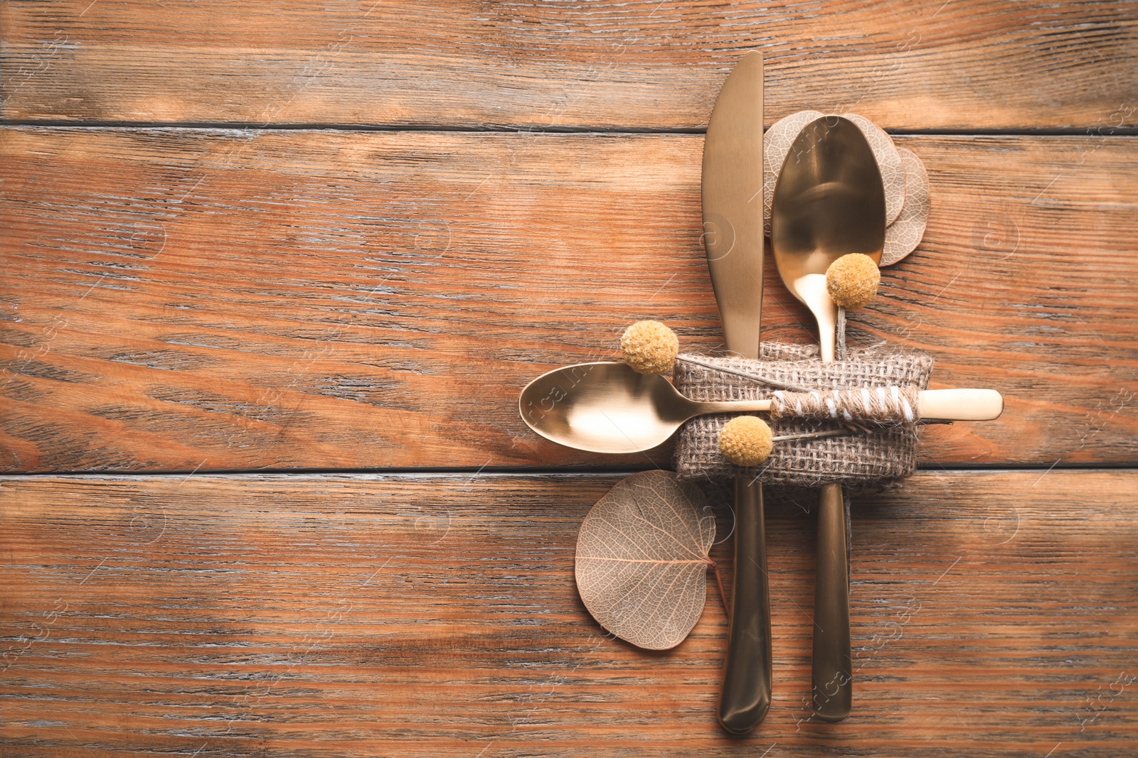 Photo of Set of cutlery and autumnal decor on wooden background, flat lay with space for text. Table setting elements