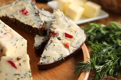 Photo of Tasty butter with dill, chili pepper and rye bread on table, closeup