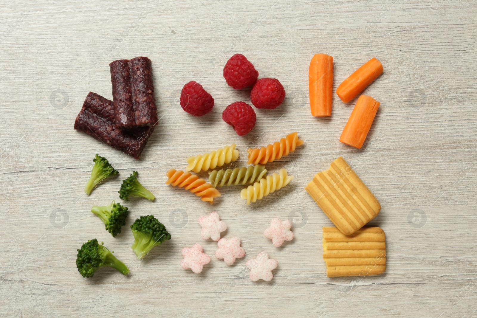 Photo of Set of different finger foods for baby on beige wooden table, flat lay