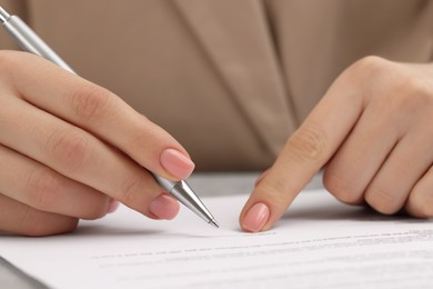 Photo of Woman signing document at table, closeup view