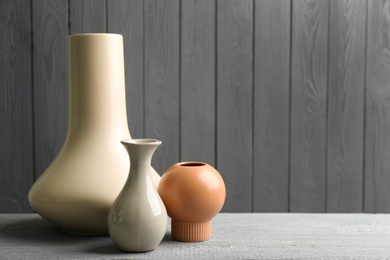 Stylish ceramic vases on grey wooden table. Space for text