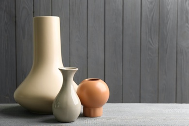 Photo of Stylish ceramic vases on grey wooden table. Space for text