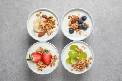 Bowls with yogurt, granola and different fruits on gray background, top view