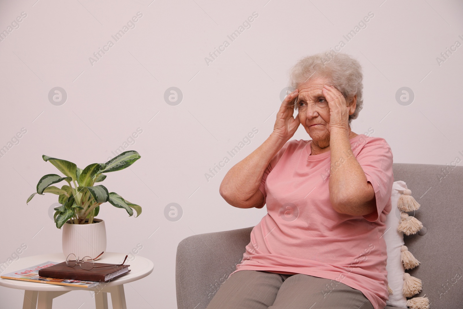 Photo of Senior woman with headache sitting on sofa at home