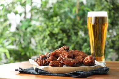 Photo of Tasty roasted chicken wings served with beer on wooden table