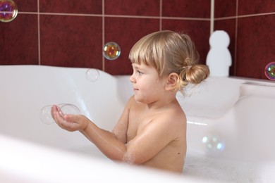 Photo of Little girl having fun in bathtub at home