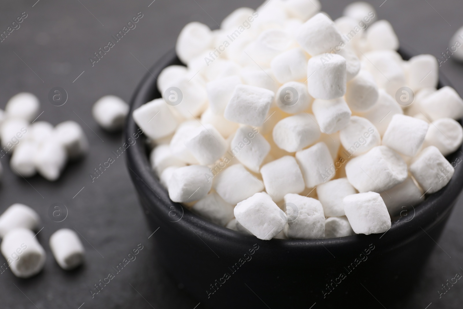 Photo of Bowl with delicious marshmallows on black background, closeup