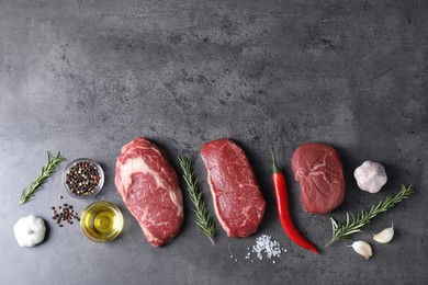 Photo of Raw beef steaks, oil and spices on grey table, flat lay. Space for text