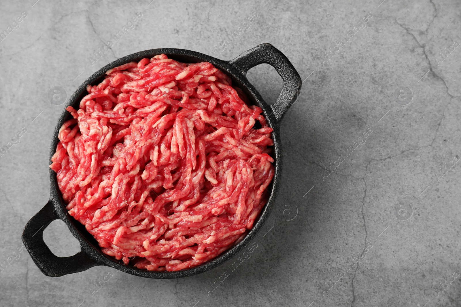 Photo of Raw ground meat in bowl on grey table, top view. Space for text