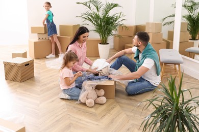 Happy family unpacking moving boxes in new house