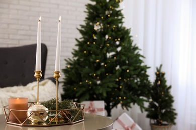 Burning candles and fir branch on table indoors, space for text. Christmas celebration