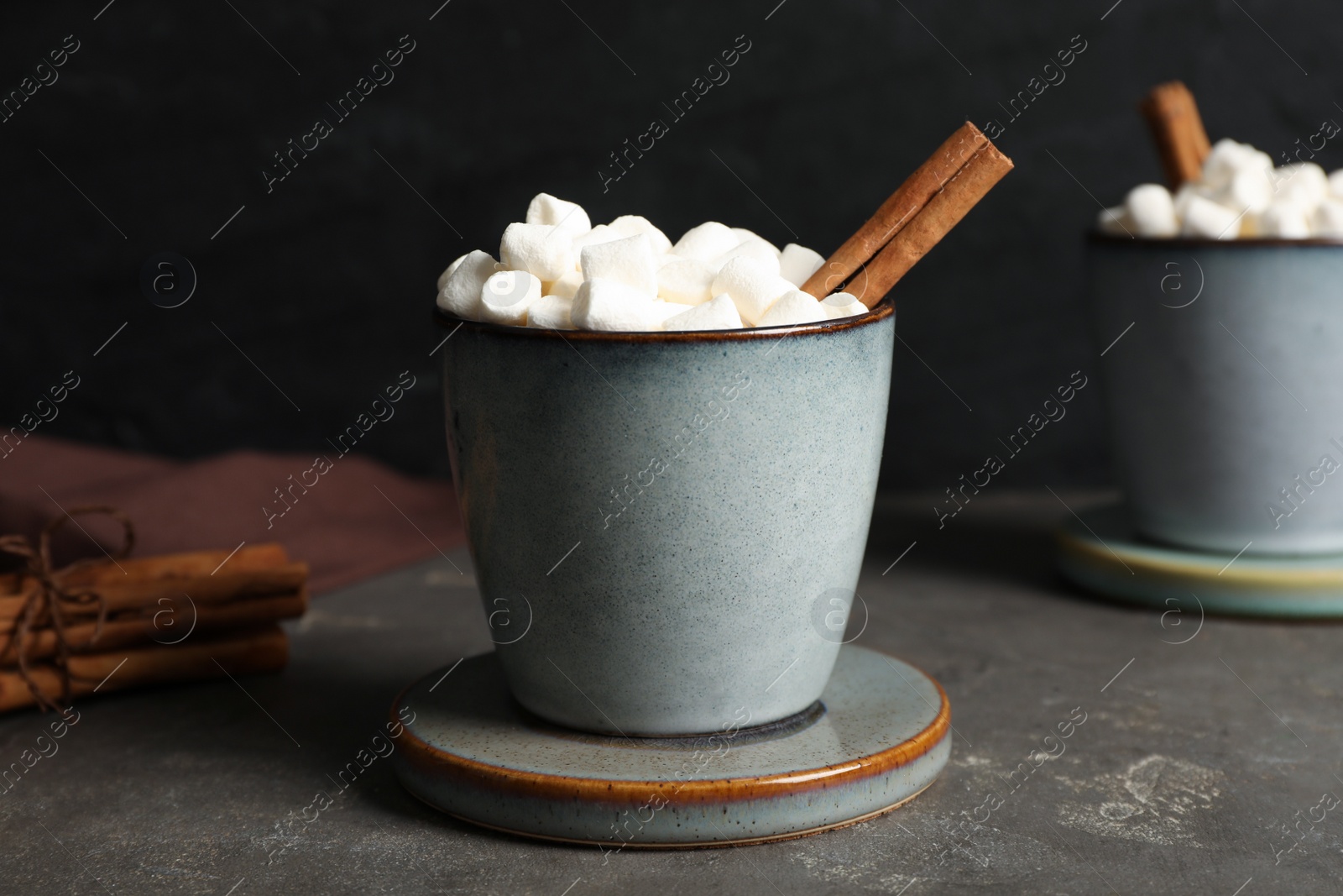 Photo of Mug of delicious drink with marshmallows and stylish cup coaster on grey table