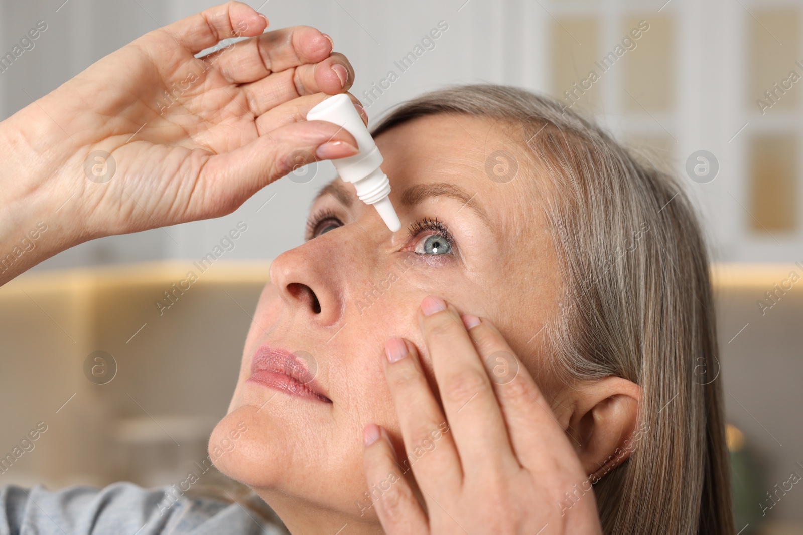 Photo of Woman applying medical eye drops at home