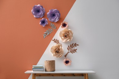 Books and holder on table near color wall with floral decor