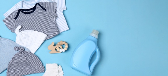 Photo of Flat lay composition with bottle of detergent and children's clothes on light blue background