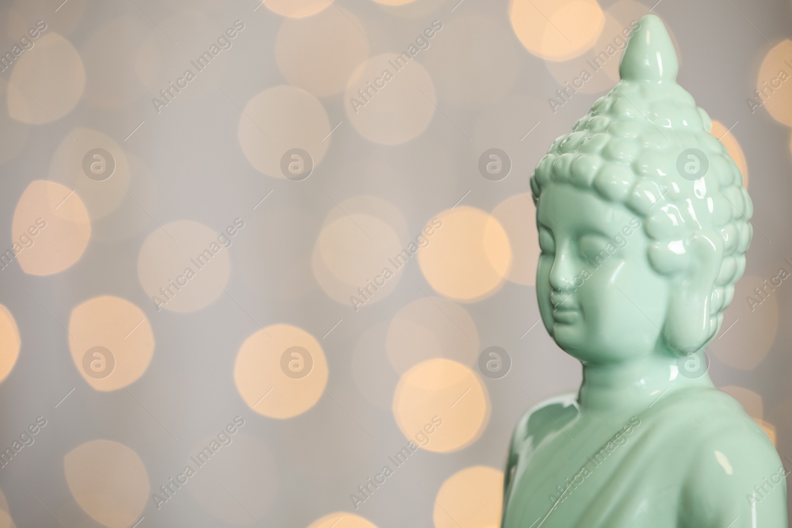 Photo of Buddha statue against blurred lights, closeup. Space for text
