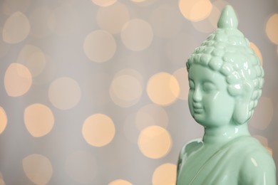 Buddha statue against blurred lights, closeup. Space for text