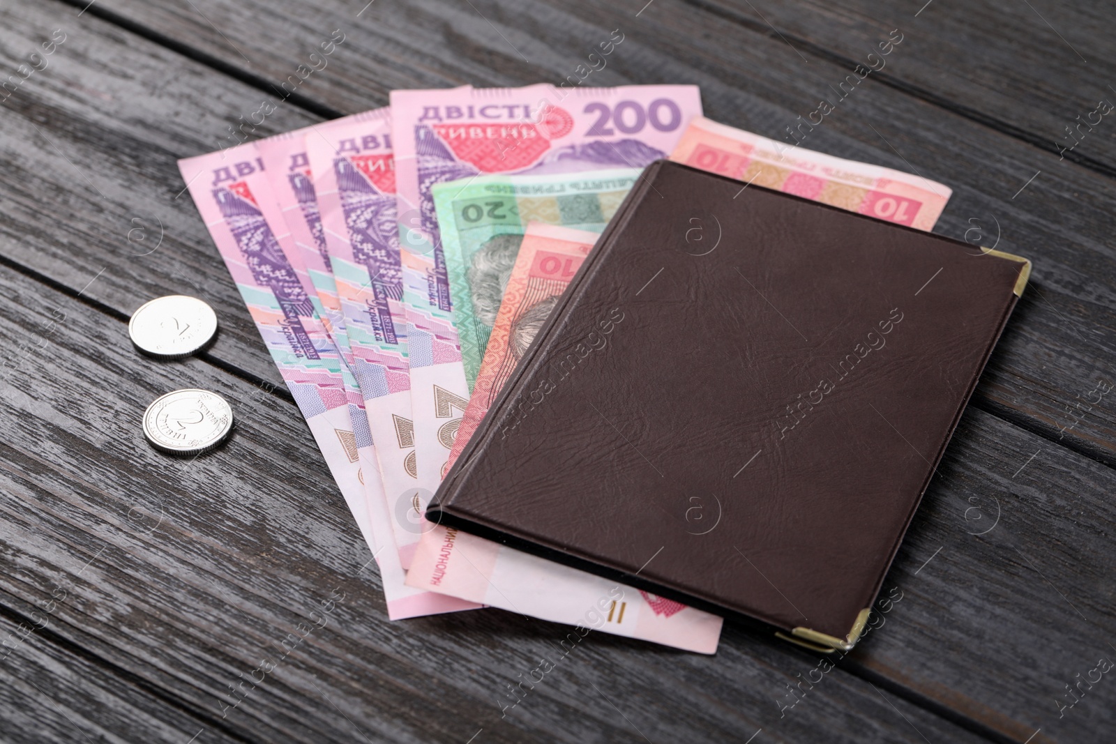 Photo of Pension certificate with Ukrainian money on black wooden background