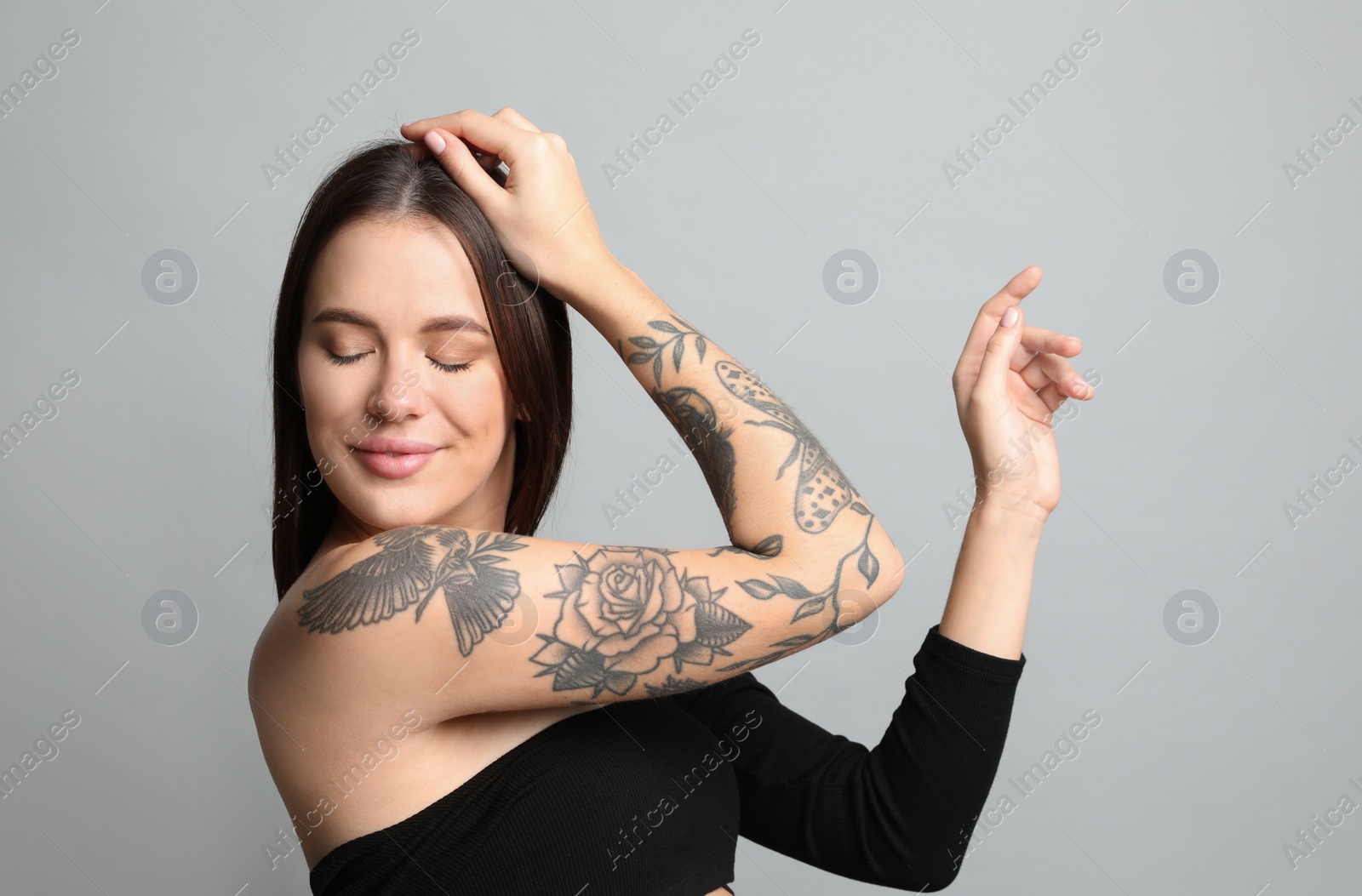 Photo of Beautiful woman with tattoos on arm against grey background