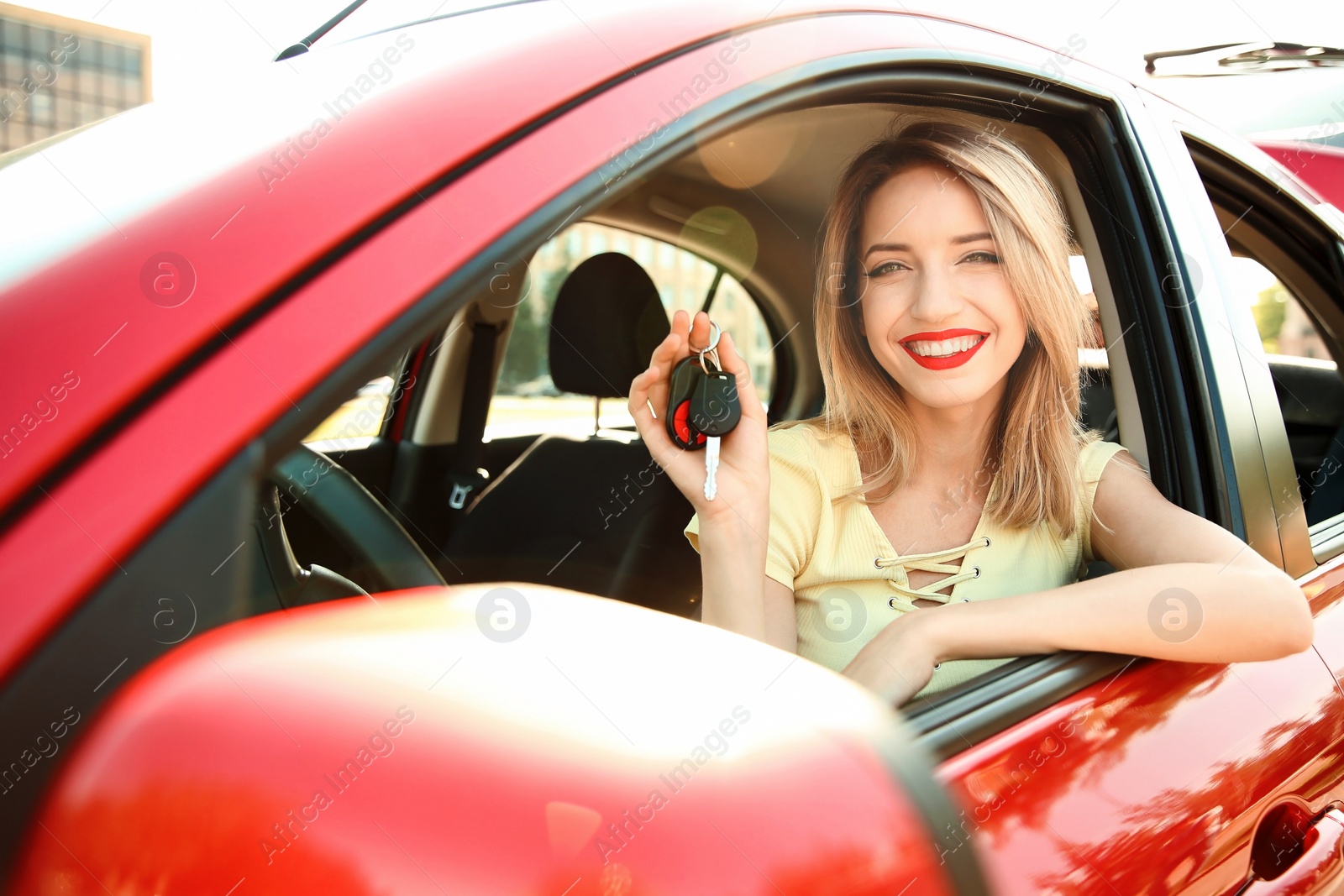 Photo of Young woman with car key on driver's seat of automobile