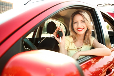 Photo of Young woman with car key on driver's seat of automobile