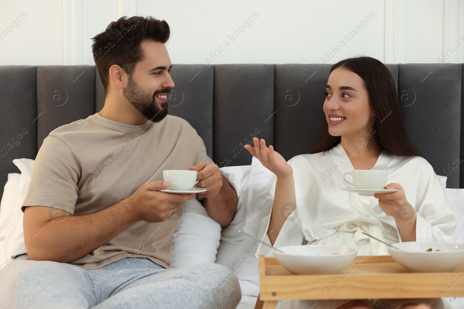 Photo of Happy couple having breakfast on bed at home