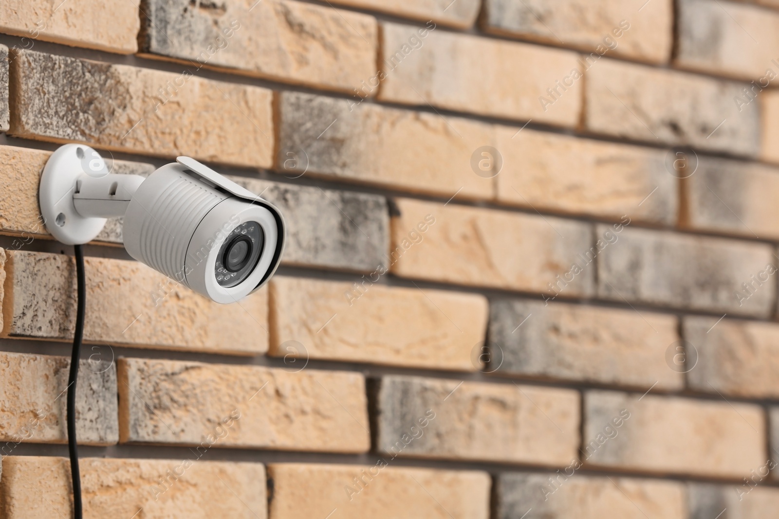 Photo of Modern security CCTV camera on brick wall