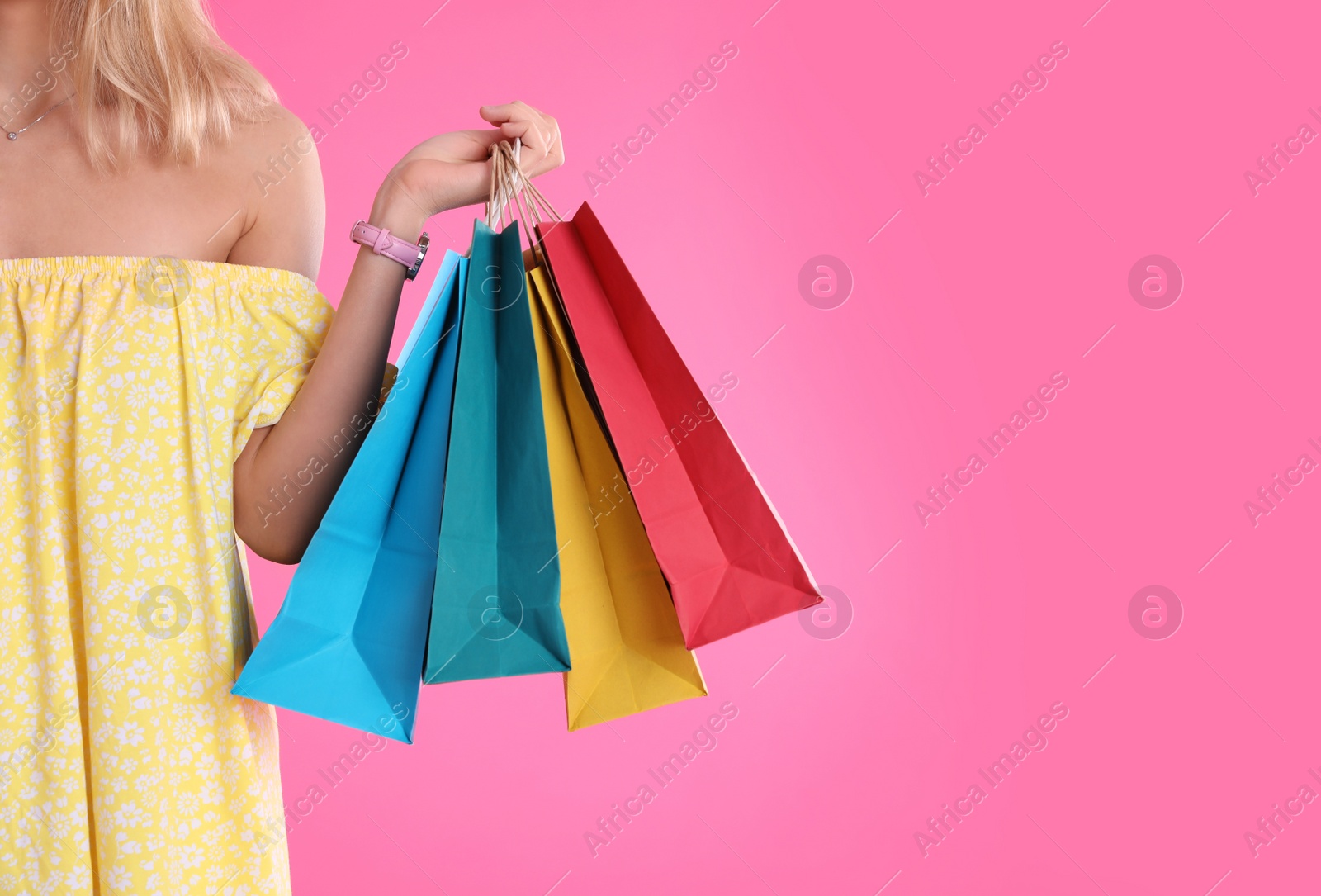 Photo of Young woman with shopping bags on color background, closeup. Space for text