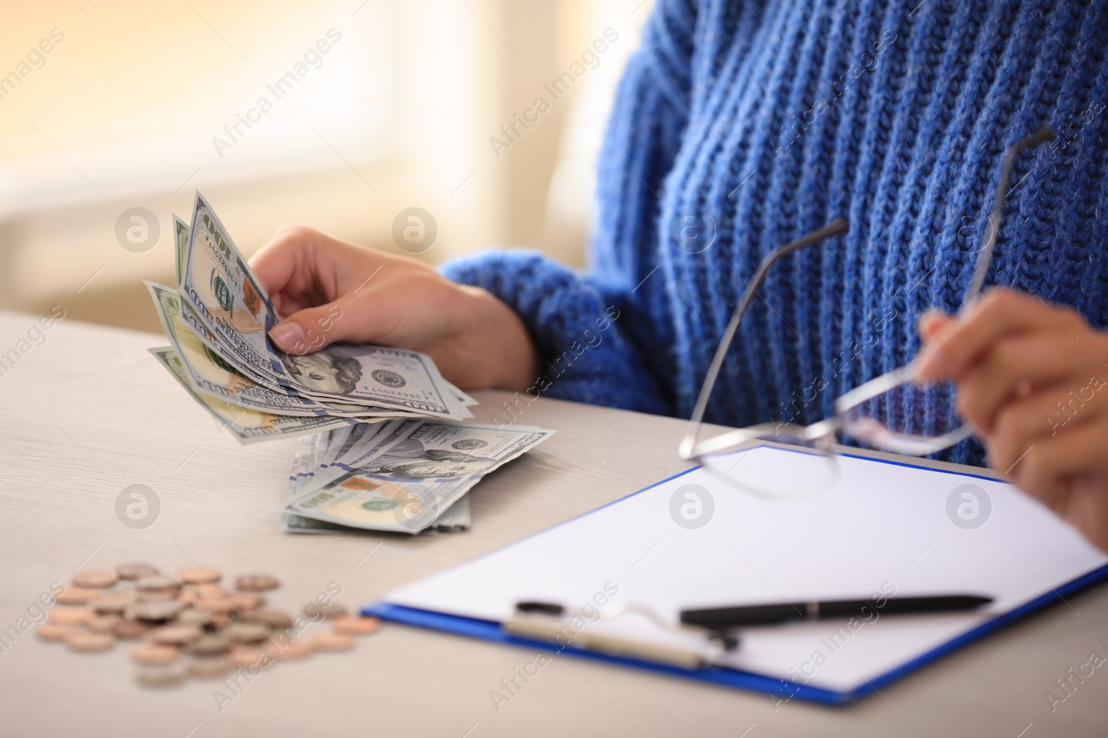 Photo of Woman with money and glasses at wooden table, closeup