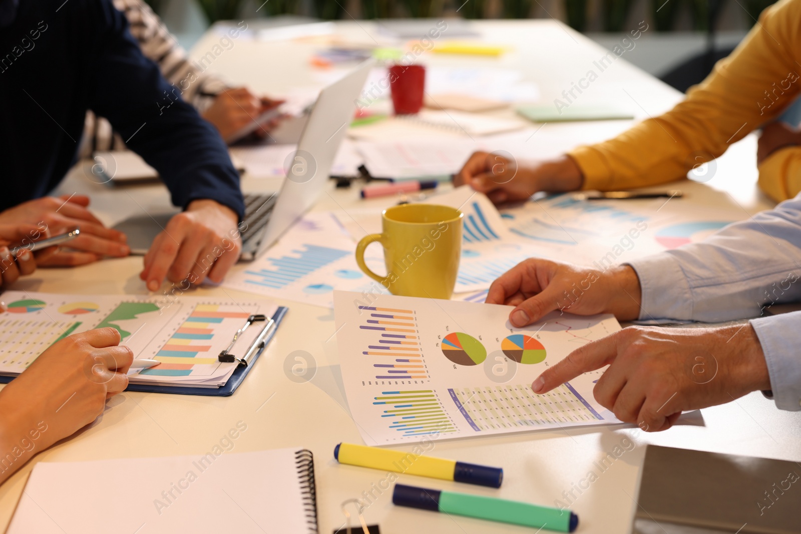 Photo of Team of employees working with charts at table, closeup. Startup project