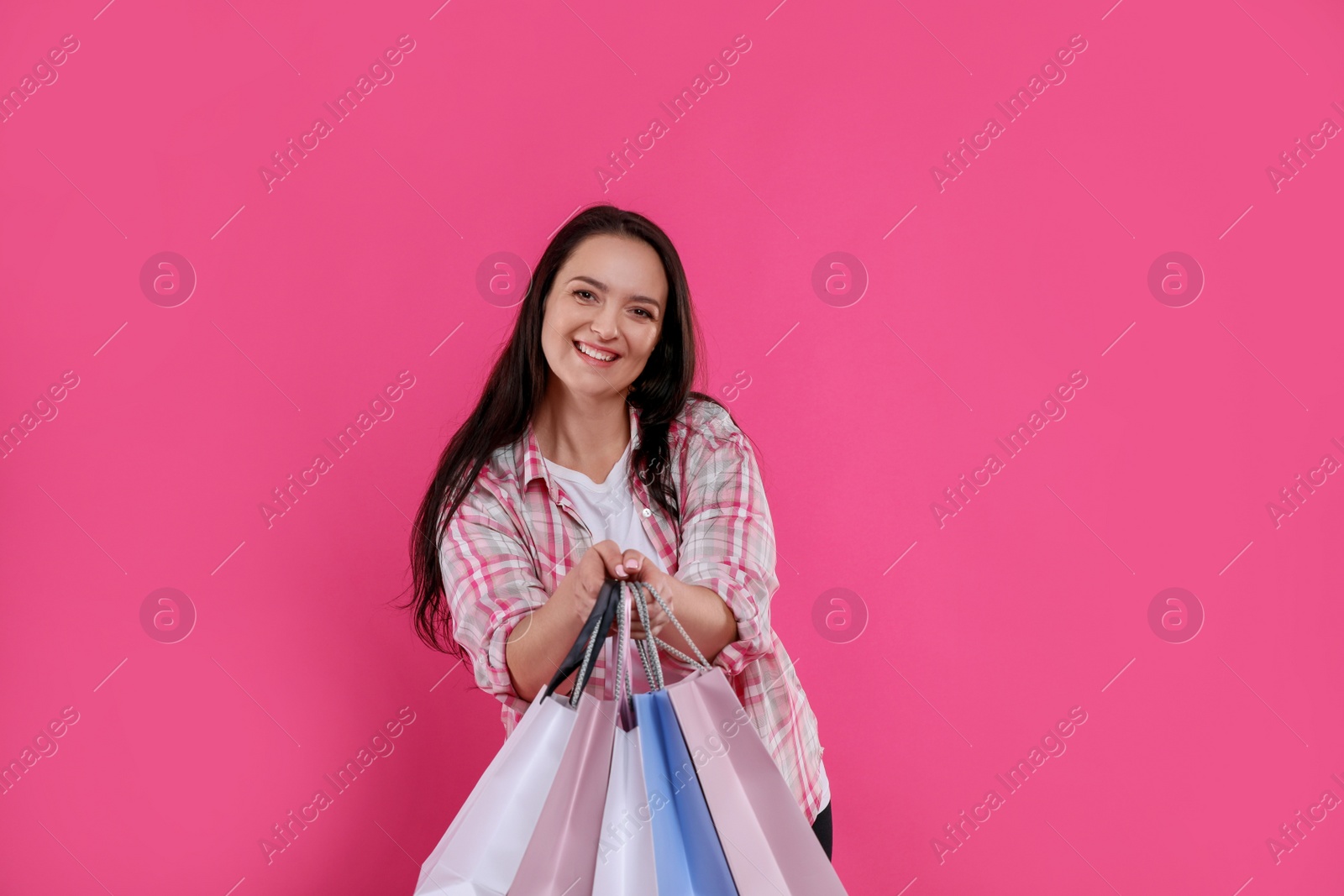 Photo of Beautiful overweight woman with shopping bags on pink background
