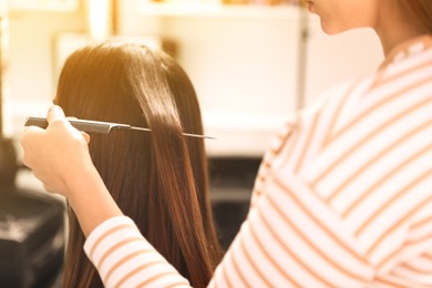 Image of Professional hairdresser working with client in beauty salon, closeup