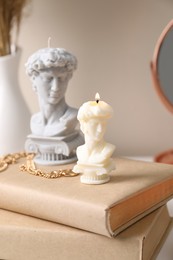 Photo of Beautiful David bust candles and books on table