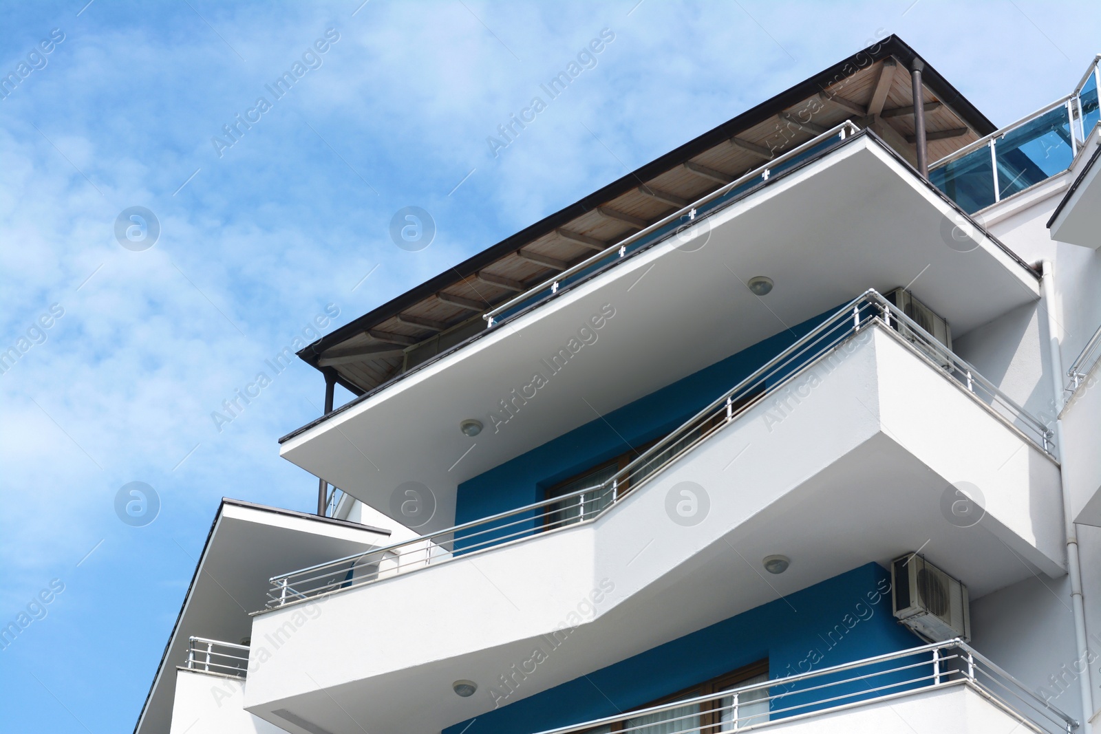 Photo of Exterior of beautiful building with balconies against blue sky, low angle view