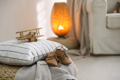 Photo of Wooden airplane and cute child's boots on pouf in baby room, closeup. Space for text