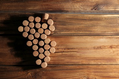 Photo of Grape made of wine bottle corks on wooden table, top view. Space for text