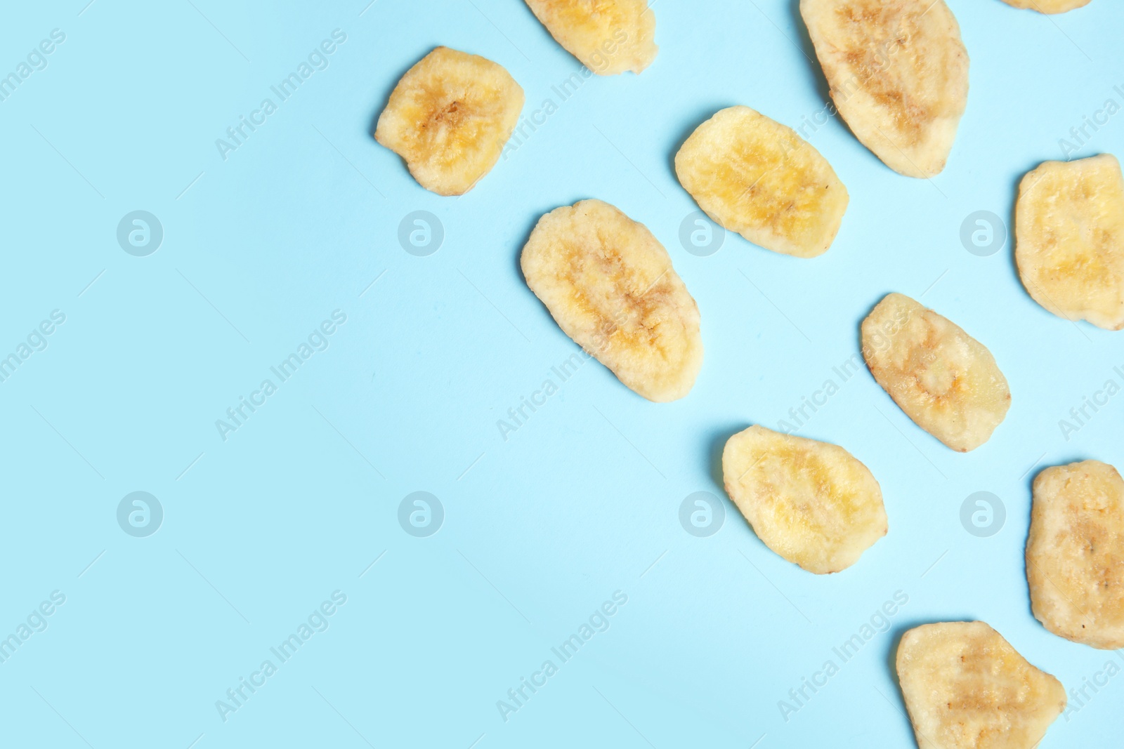 Photo of Flat lay composition with banana slices on color background, space for text. Dried fruit as healthy snack