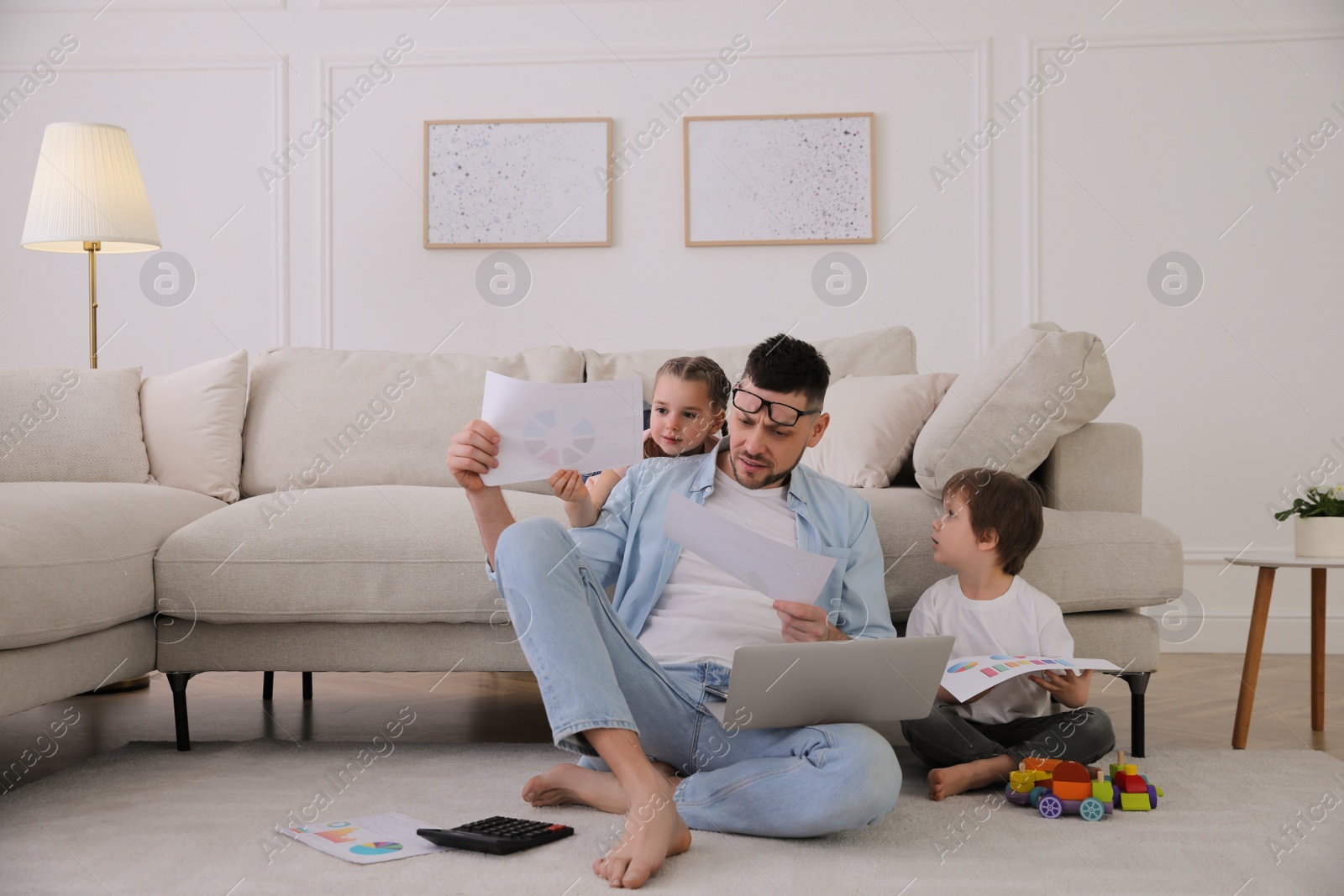 Photo of Overwhelmed man combining parenting and work at home