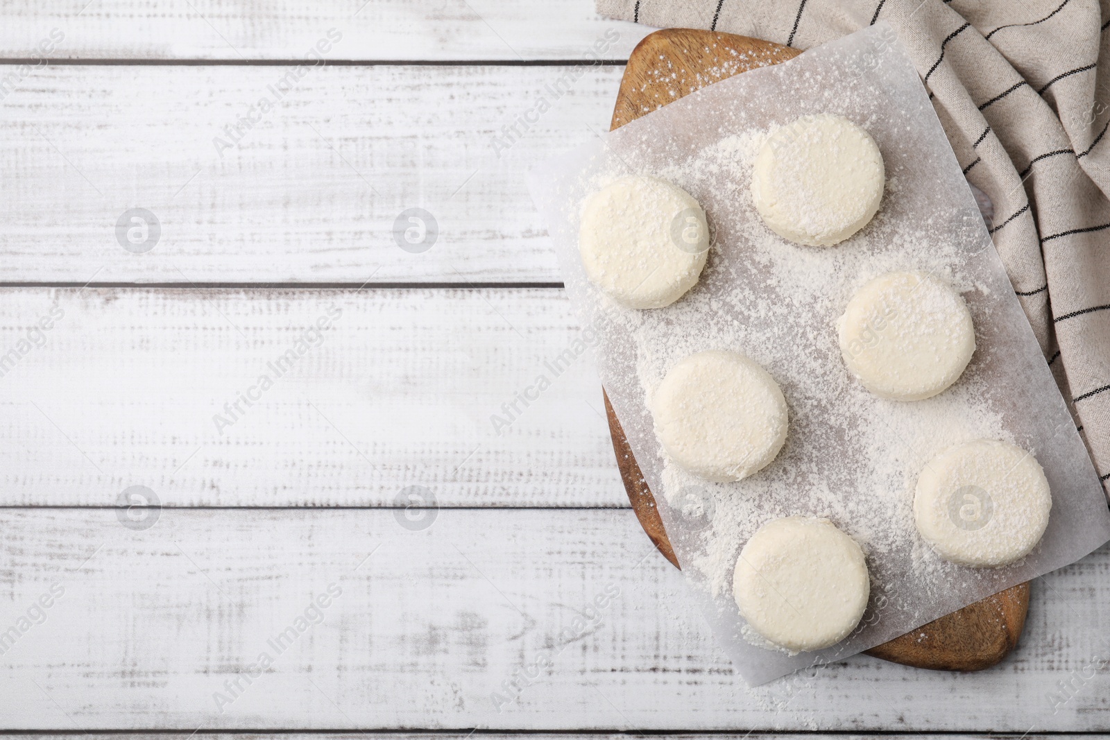 Photo of Uncooked cottage cheese pancakes on white wooden table, top view. Space for text