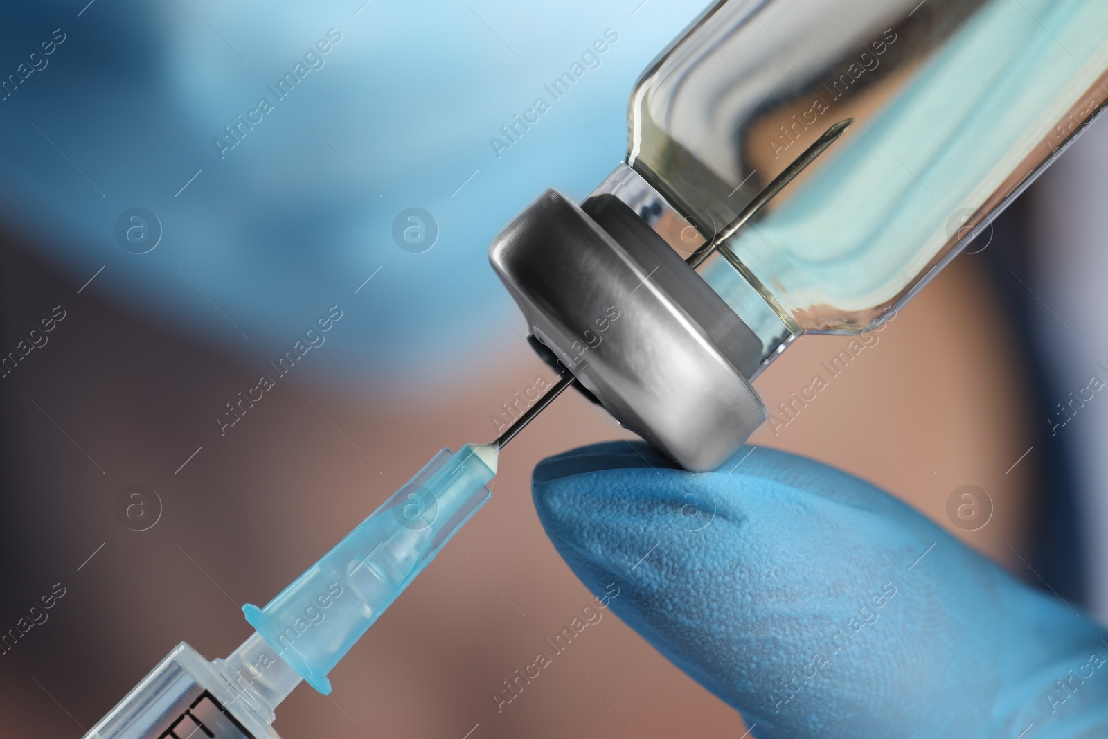 Photo of Doctor filling syringe with medication from glass vial, closeup