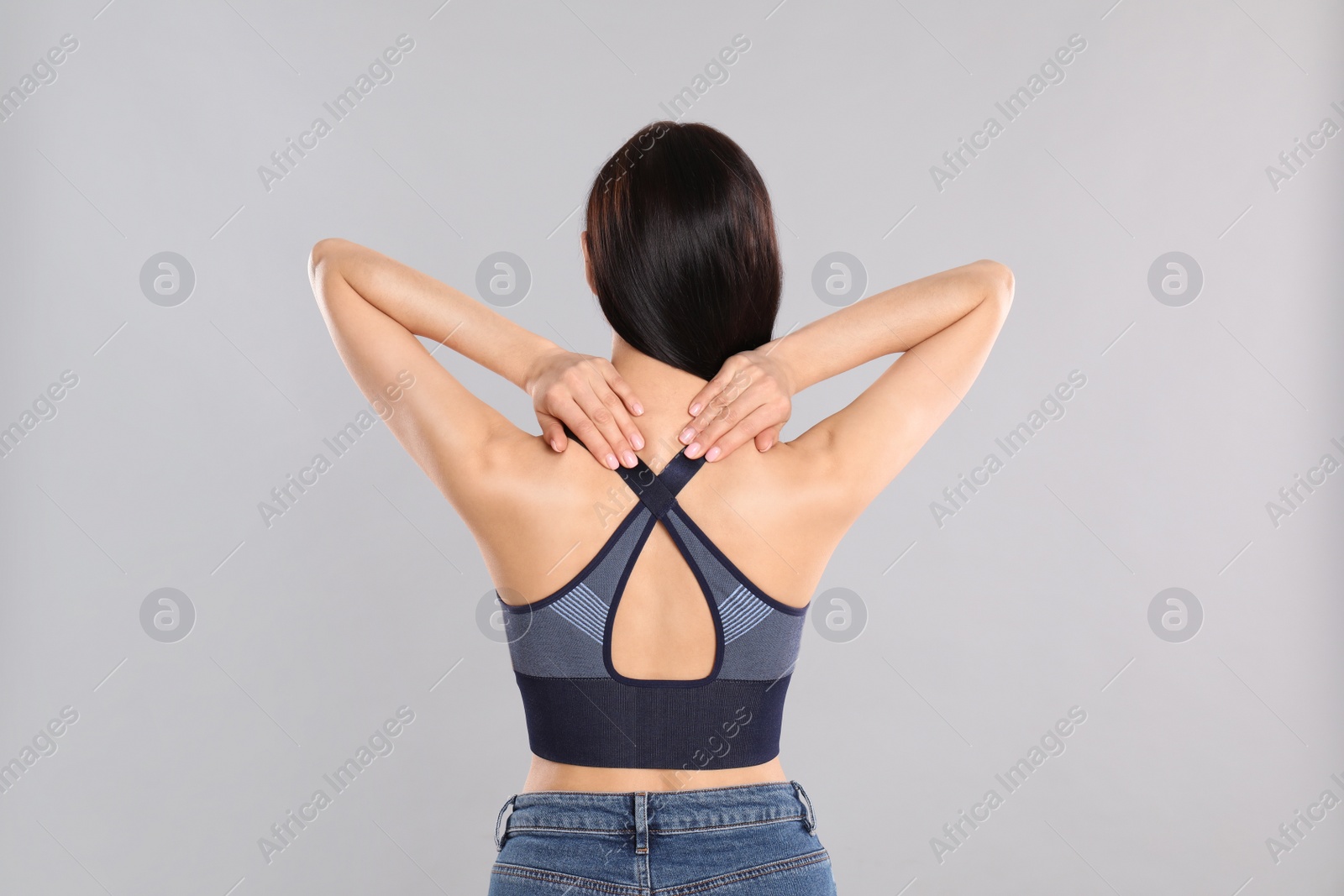 Photo of Woman suffering from pain in neck on light grey background. Visiting orthopedist