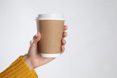 Woman holding takeaway paper coffee cup on white background, closeup