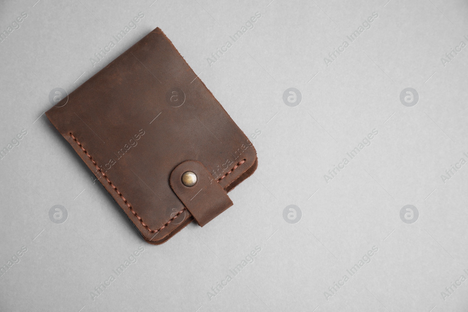 Photo of Stylish brown leather wallet on light grey background, top view. Space for text