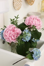 Photo of Vase with beautiful hortensia flowers in kitchen sink