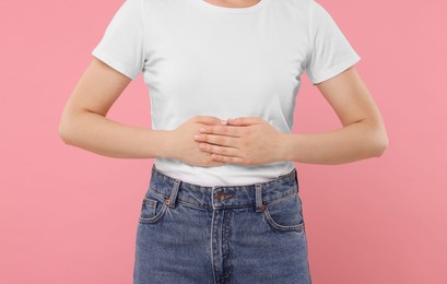 Photo of Woman suffering from abdominal pain on pink background, closeup. Unhealthy stomach