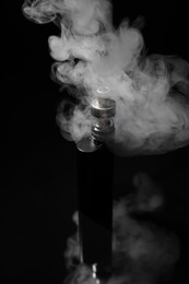 Photo of Electronic cigarette and smoke on black background
