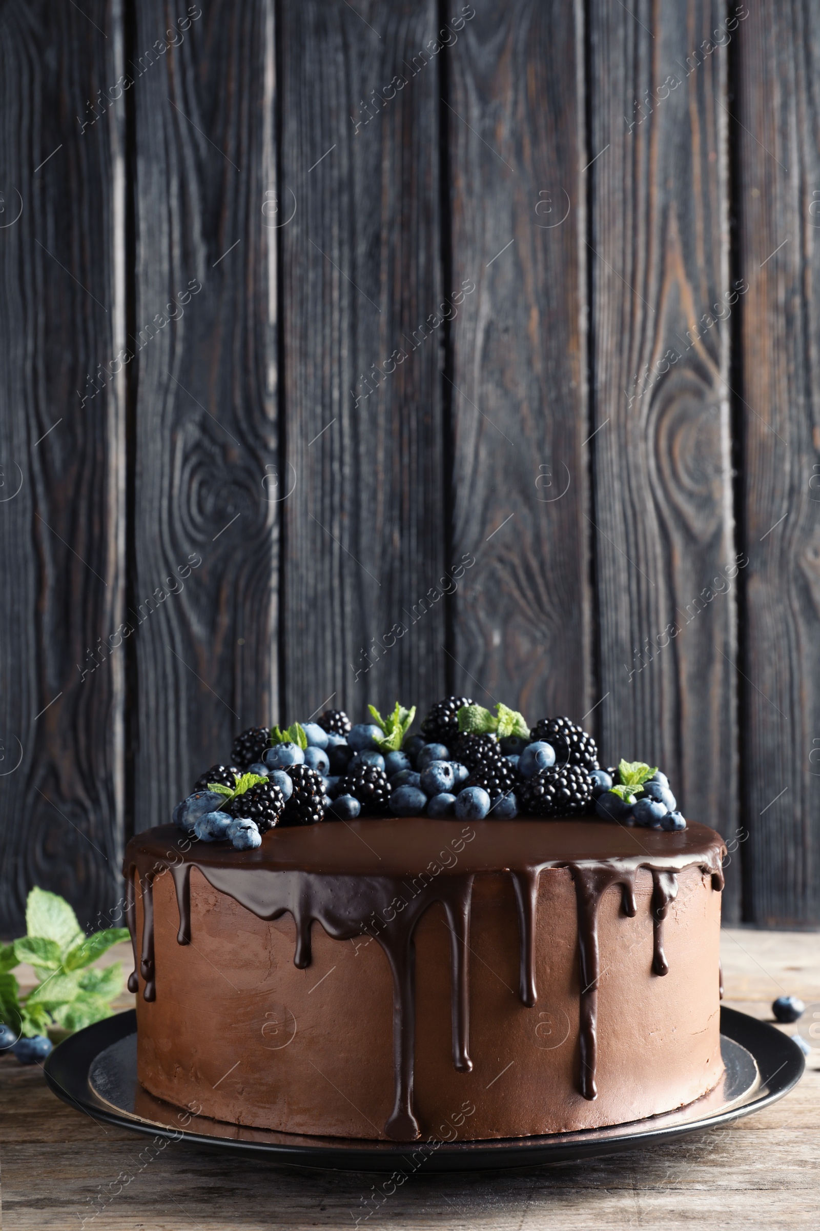 Photo of Fresh delicious homemade chocolate cake with berries on table against wooden background